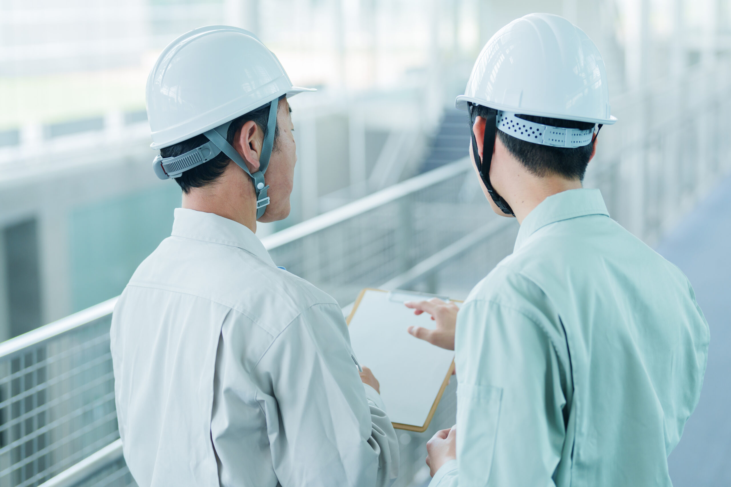 資料を見ながら相談する2人の作業員のイメージ